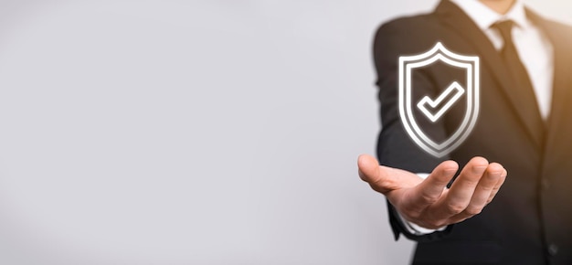 Фото Мужская рука держит защитный щит с галочкой на синем фоне. компьютер безопасности сети защиты и безопасность вашей концепции данных.