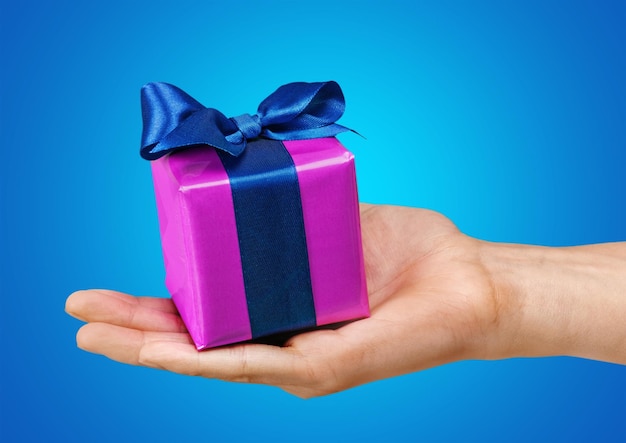 Male hand holding purple gift box with blue ribbon