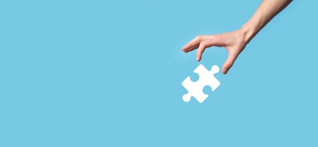 Male hand holding puzzle icon on blue background