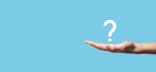 Male hand holding question mark icon on blue background