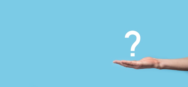 Male hand holding question mark icon on blue background.