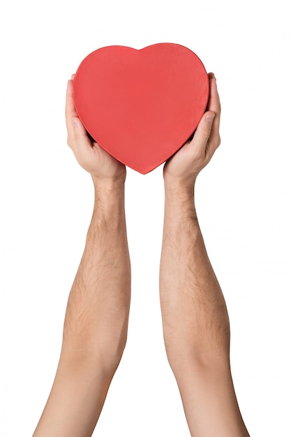 Male hand holding a red box in the shape of a heart. Isolated