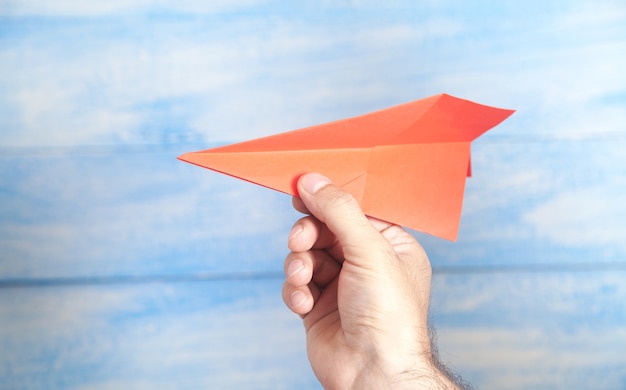 Male hand holding red paper airplane.