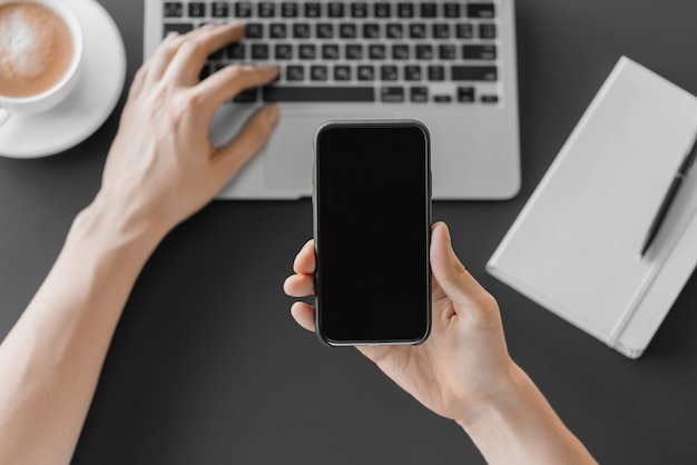 Male hand holding a smartphone in the office