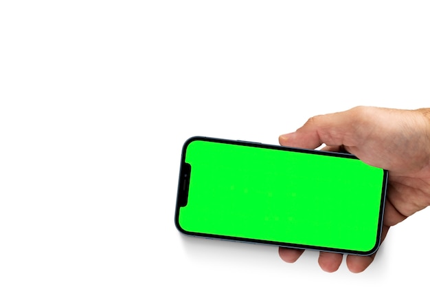 Male hand holding a smartphone with a green screen. Chroma key. Isolated on a white background.