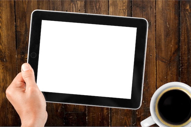 Male hand holding a tablet PC with coffee on table