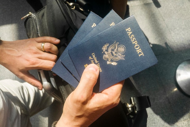 Foto mano maschile che tiene tre passaporti statunitensi in aeroporto durante la procedura di check-in