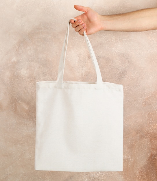 Premium Photo | Male hand holding tote bag against brown background