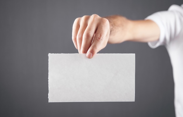 Male hand holding white blank paper.