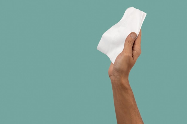 Male hand holding white cleaning cloth on green background