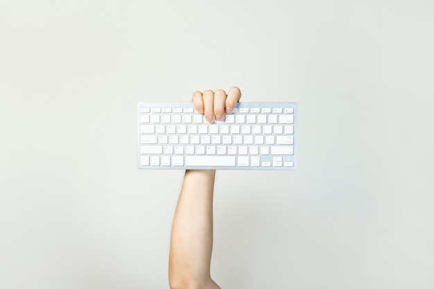 Male hand holds a keyboard on a light isolated