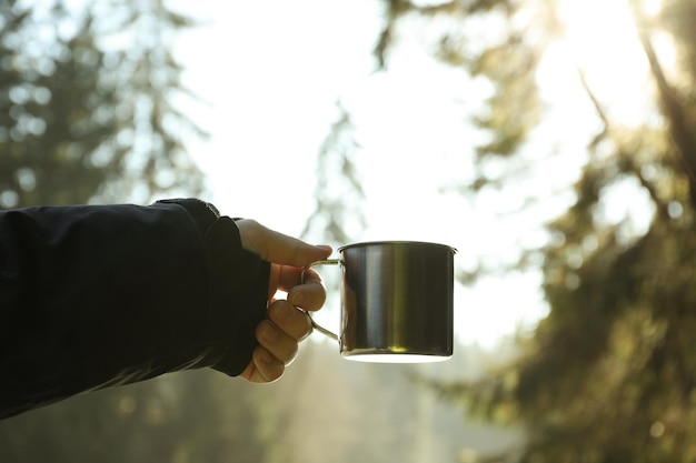 Male hand holds metal cup of drink outdoor