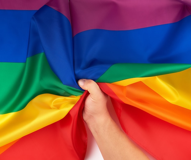 La mano maschile detiene una bandiera arcobaleno simbolo della comunità lgbt