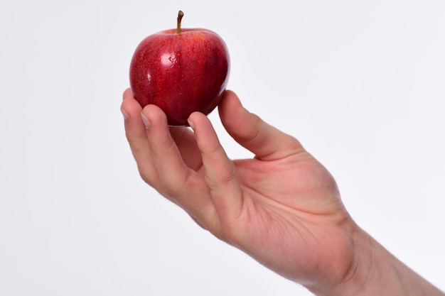 Мужская рука держит красное яблоко Яблоко яркого сочного цвета
