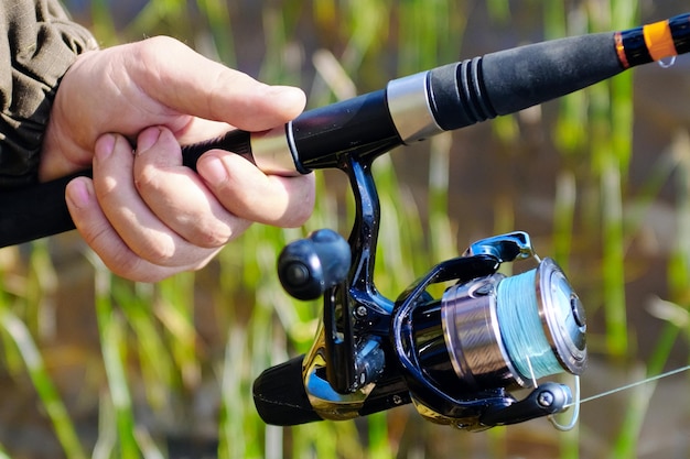 Male hand holds spinning with reel closeup