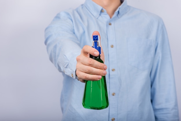 Male hand holds spray gun. Green spray bottle. Front view.