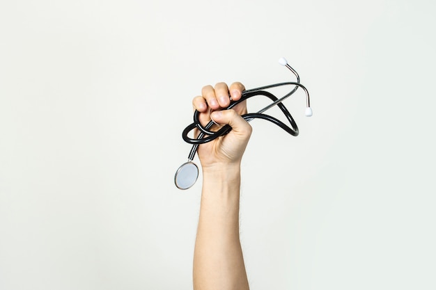 Male hand holds a stethoscope on a light