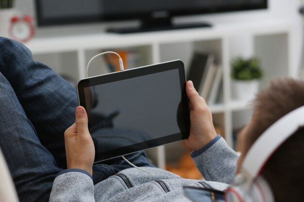 Male hand holds tablet in home setting while