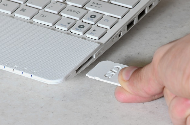 A male hand inserts a white compact SD card into the corresponding 