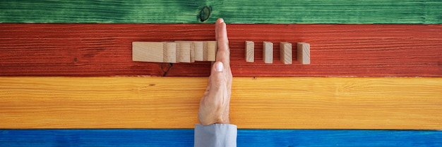 Male hand intervening to stop dominos from collapsing