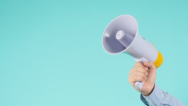 Male Hand is hold megaphone and wear blue shirt on green or mint or Tiffany Blue background.