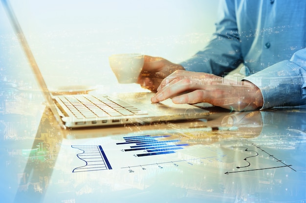 The male hand on the keyboard and hand with coffee on the surface of table with pen