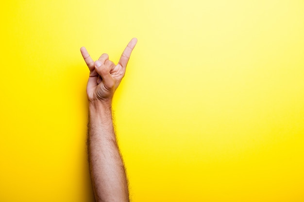 Photo male hand making signs with his fingers on yellow background