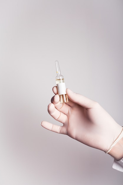 A male hand in a medical glove holds an ampoule with antivirus