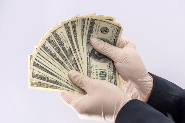 Male hand in medical glove holds us money bills for protection
against covid-19 (coronavirus) isolated.