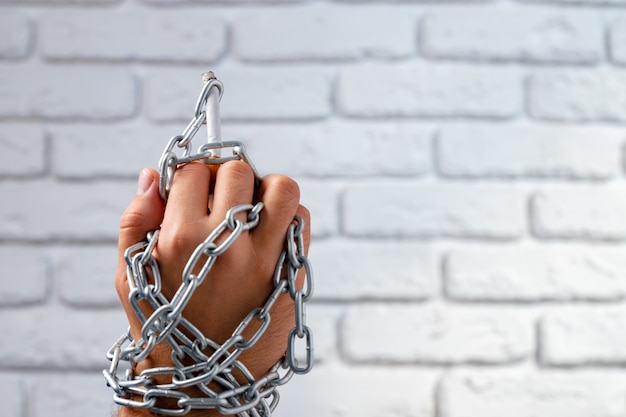 Male hand in metal chains holding cigarette