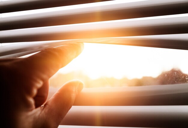 Foto gelosia aperta della mano maschio nel tramonto