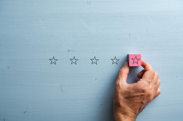 Male hand placing a pink wooden block with star shape on it in a line of five