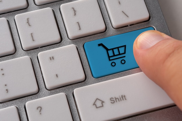 Male hand pressing keyboard button with shopping cart.