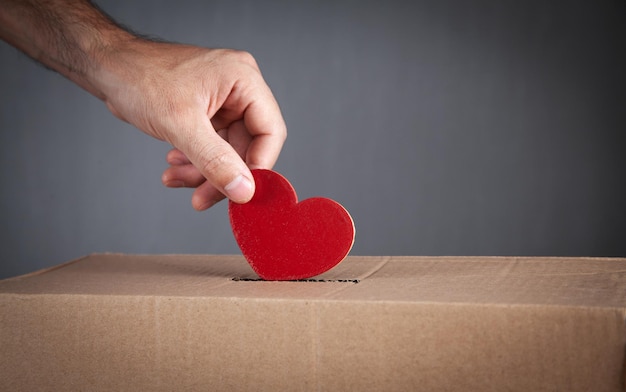 Male hand putting red heart in box