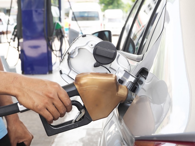 Mano maschile ricarica carburante per auto su una stazione di rifornimento di gas