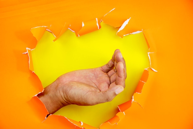 Male hand ripped orange paper background