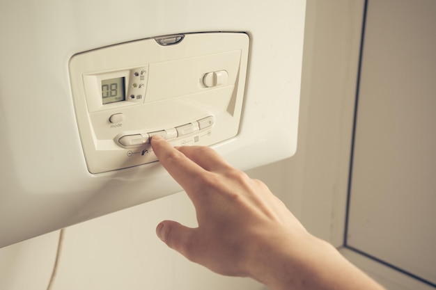 Male hand setting temperature on a heating boiler construction