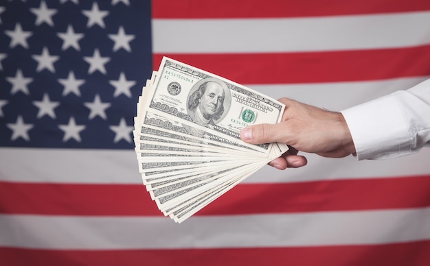 Male hand showing dollars on the American flag