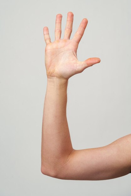 Male hand showing five fingers against gray background