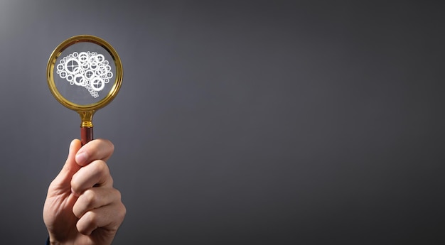 Male hand showing magnifying glass with a human brain