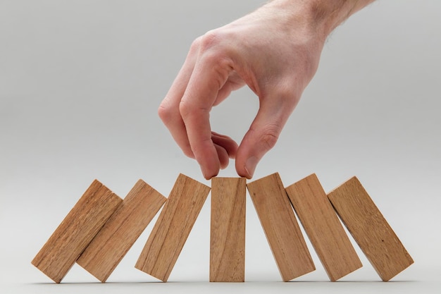 Male hand stopping wooden blocks falling over