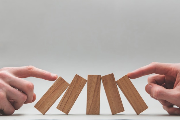 Male hand stopping wooden blocks falling over