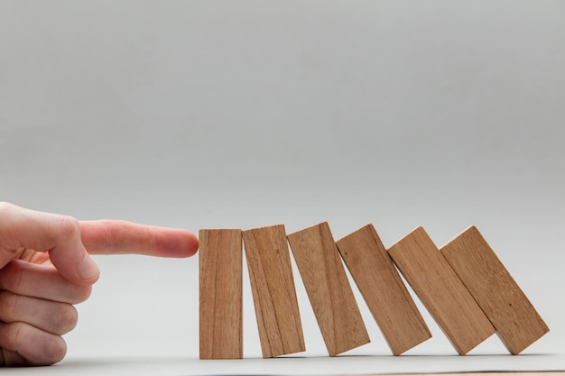 Male hand stopping wooden blocks falling over