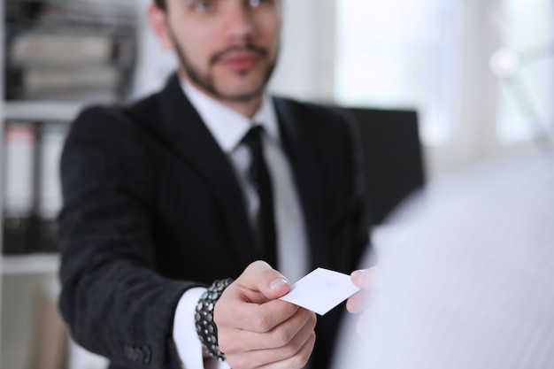 Male hand in suit give blank calling card to female visitor closeup. 