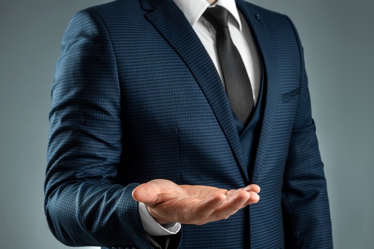 スーツを着た男性の手は、灰色の背景に手のひらを上に向けたジェスチャーを示しています。リクエスト、破産、クローズアップの概念。