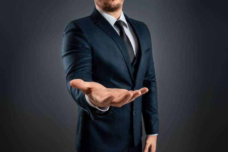スーツを着た男性の手は、灰色の背景に手のひらを上に向けたジェスチャーを示しています。リクエスト、破産、クローズアップの概念。