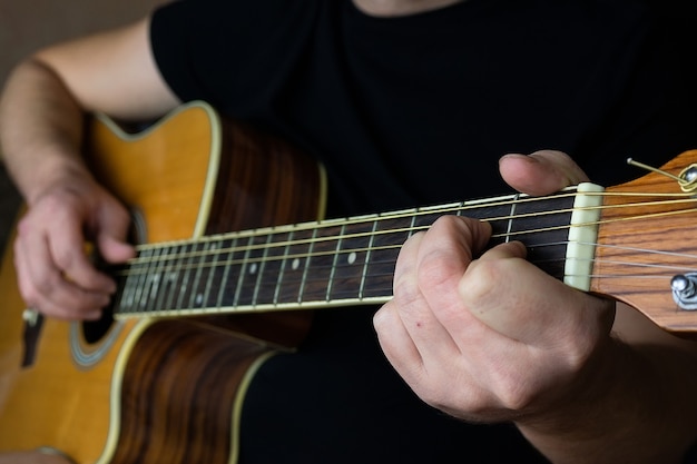 Una mano maschile durante la riproduzione di una chitarra elettroacustica