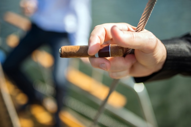 Male hand with a cigar on a yacht