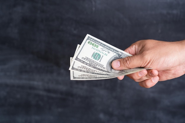 Male hand with dollars on a dark background, the concept of corruption and bribery.