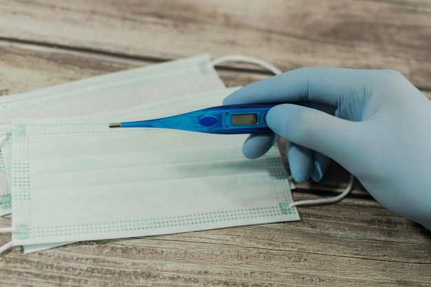 Male hand with gloves holding a thermometer Covid19 prevention